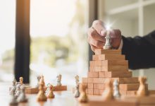 استراتيجيات تنمية التفكير الإبداعي صورة لشخص يحاول وضع قطعة شطرنج على قمة شكل هرمي